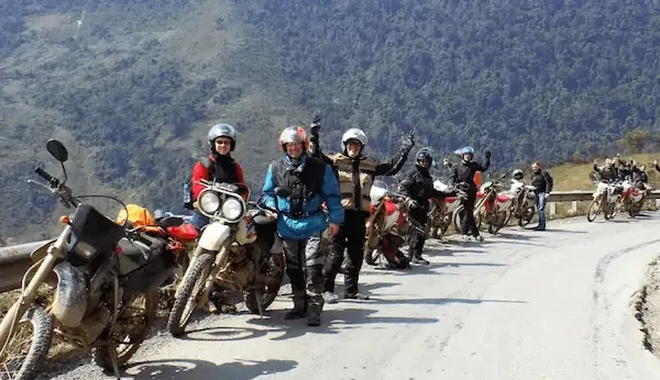 Group of expats on motorbikes riding through a lush green mountain pass - expats driving motorbike - scenic ride