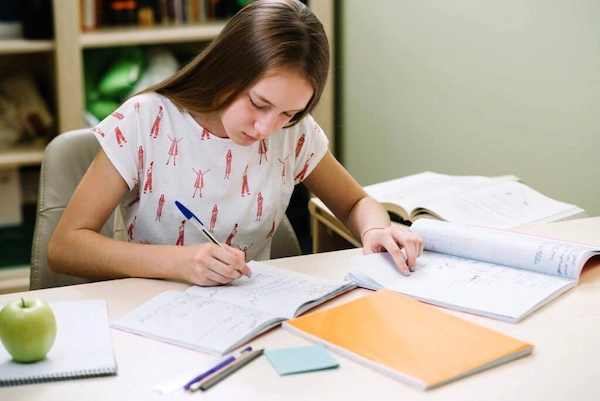 Person sitting at a desk, writing Vietnamese characters in a notebook - practice Vietnamese regularly - consistent learning